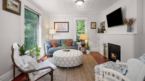 A living room with a fireplace, a sofa, a round ottoman, and a television mounted on the wall. - 2BR + 1BA, Small Town Feel, Pets Allowed (Spokane)