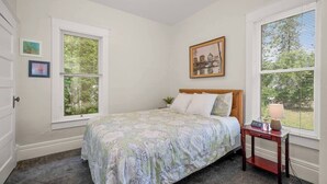 A bedroom with a bed, a bedside table, a window, and a painting on the wall. - 2BR + 1BA, Small Town Feel, Pets Allowed (Spokane)