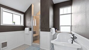Un baño moderno con una bañera independiente, ducha a ras de suelo y una ventana que proporciona luz natural.