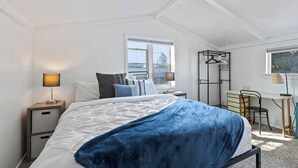 Un dormitorio con una cama, mesitas de noche, un escritorio y una silla.