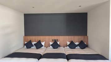 Un dormitorio amplio y moderno con cabecera de madera, varias camas y una gran pared oscura.