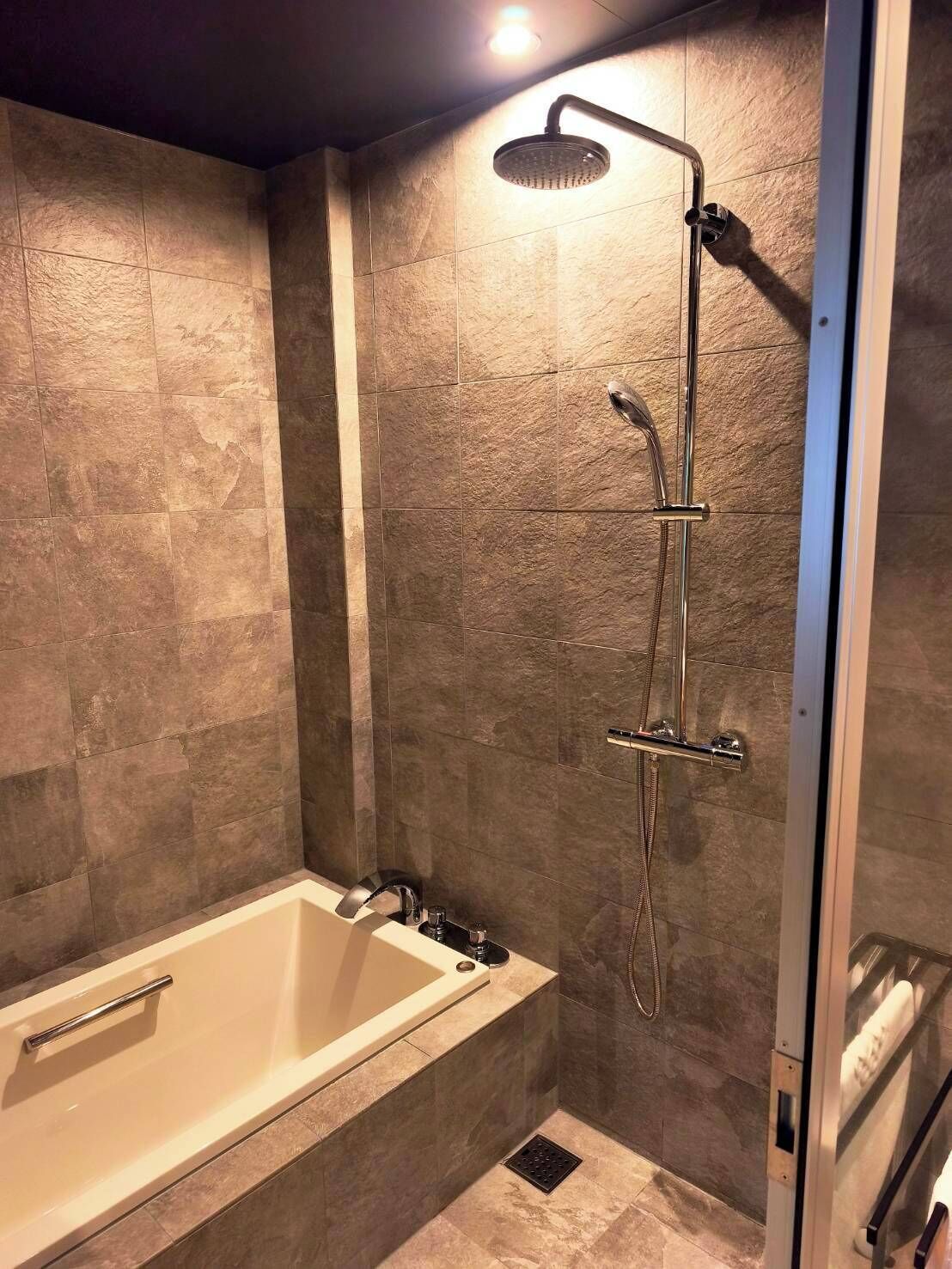 Um banheiro moderno com banheira, chuveiro e box de vidro.