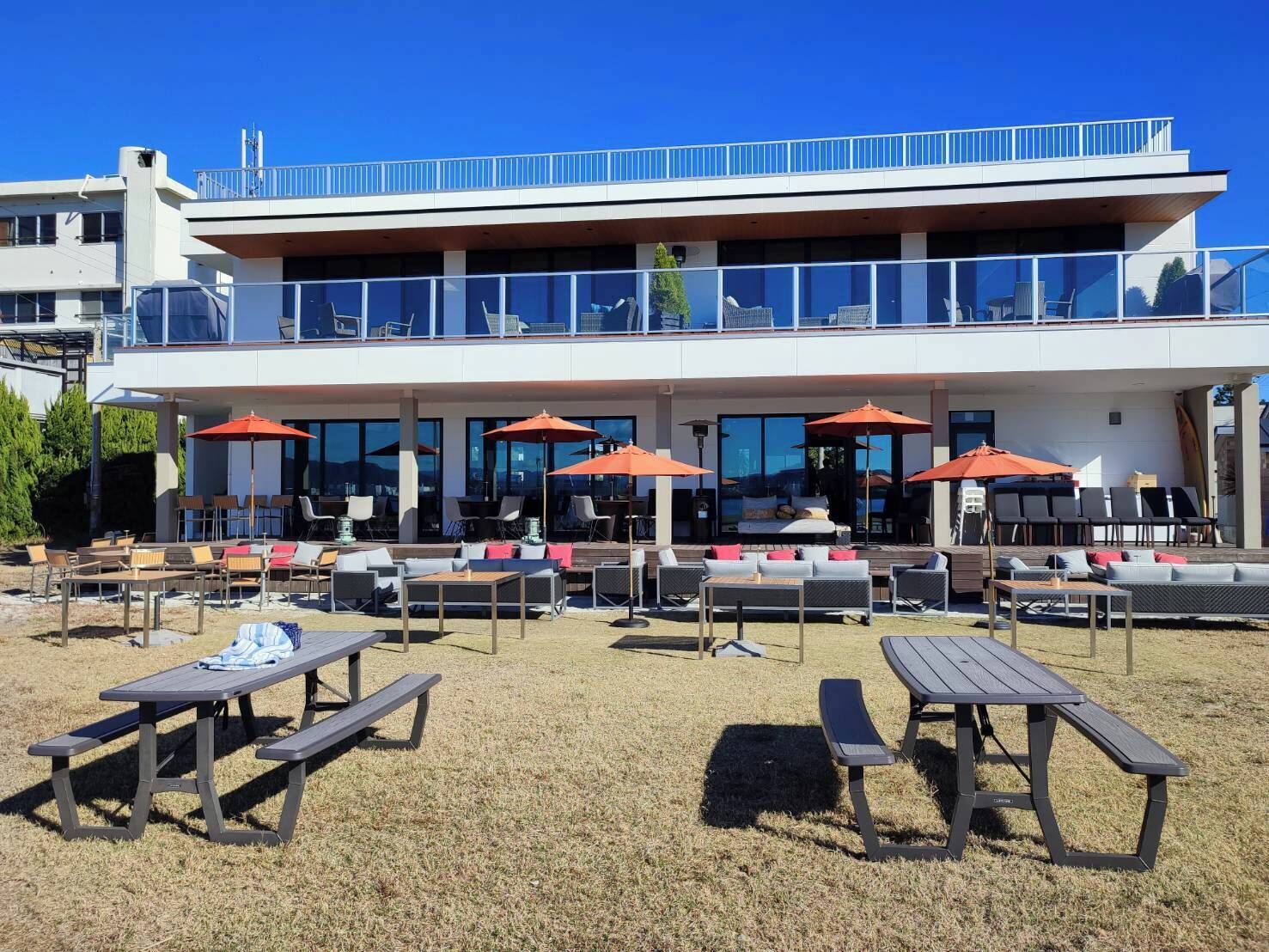 A modern building with outdoor seating and umbrellas, a covered patio area, and a pool.