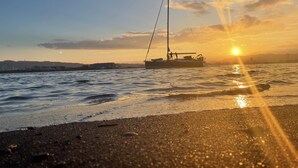 A sailboat on calm waters during sunset with a clear sky. - 'Ulalena (Shizuoka)