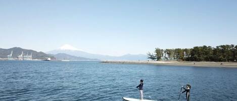 Deux personnes pratiquent le paddle sur une étendue d’eau calme, avec une montagne en arrière-plan.