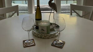 Ein Tisch mit Kerze, Flasche und zwei Gläsern mit Blick auf einen See mit Sonnenschirmen.