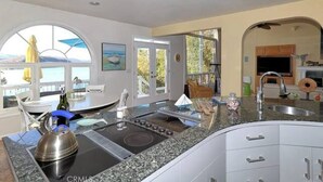 Eine moderne Küche mit Granit Arbeitsplatten, einem eingebauten Herd und einem großen Fenster mit Blick auf eine reizvolle Landschaft.