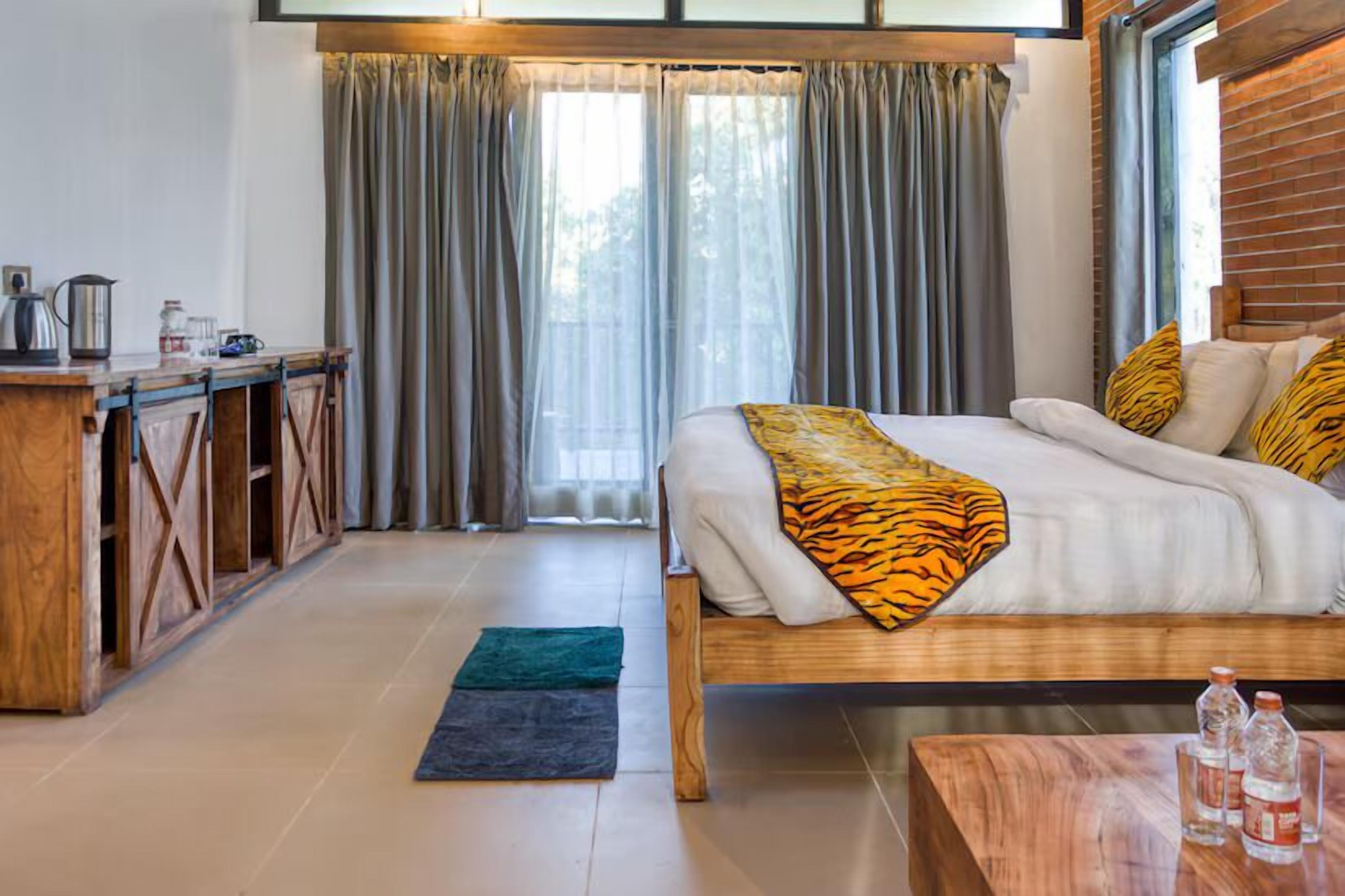 A bedroom with a wooden bed, a desk, and a window with curtains.