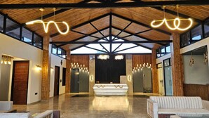 A spacious lobby with a high ceiling, a reception desk, and seating areas. - Corbett Machaan Resort (Ramnagar)