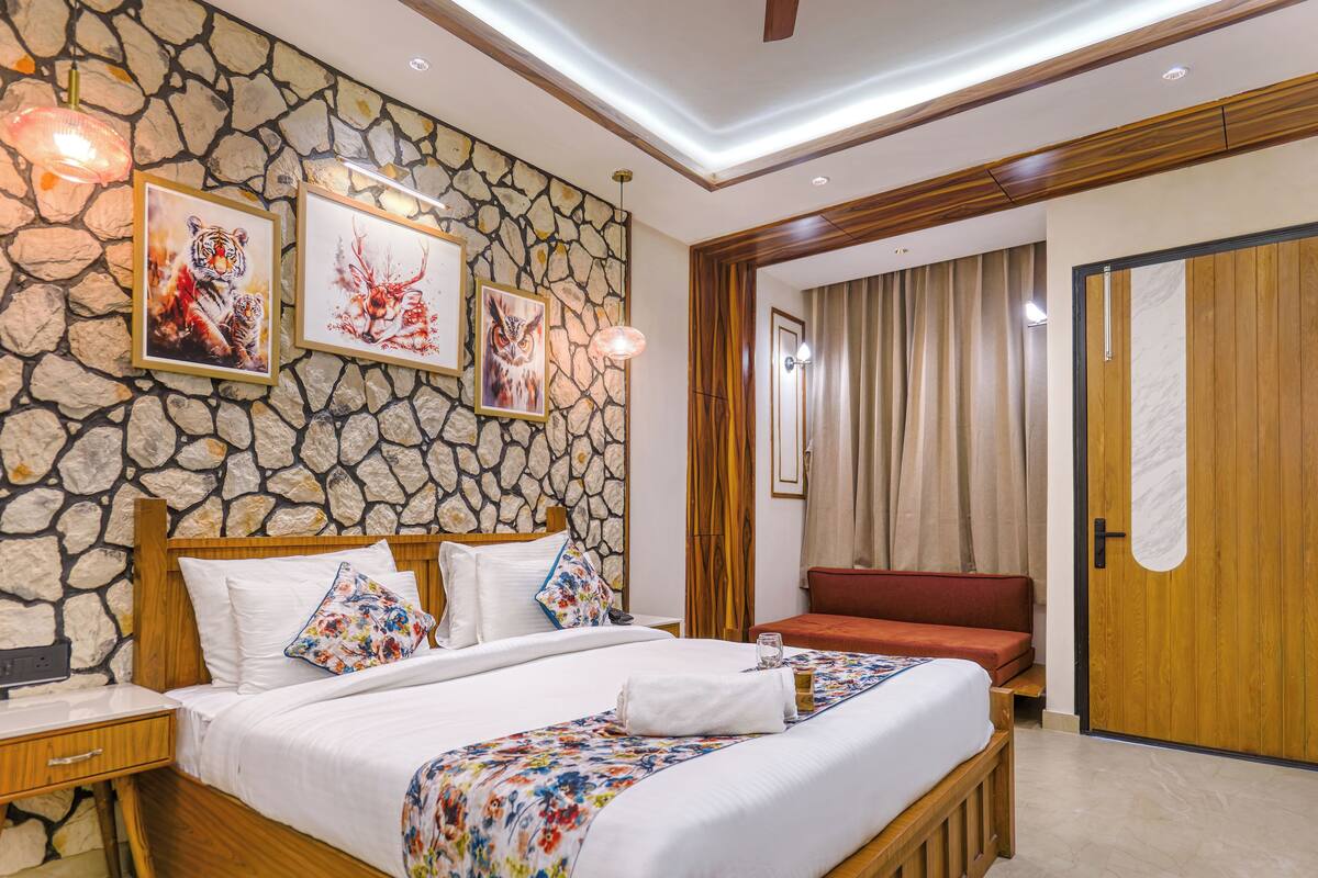 A hotel room with a stone wall, wooden bed frame, and a red sofa.