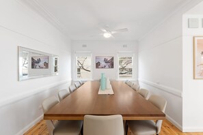 Comedor con una mesa de madera, paredes blancas y cuadros enmarcados.