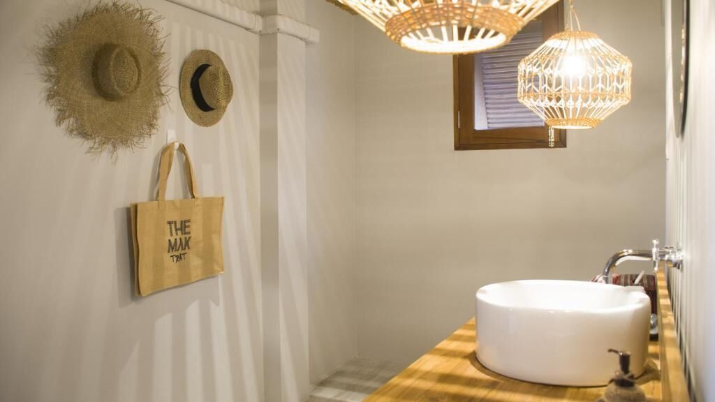 A bathroom with a round white sink, a wooden countertop, and a hanging light fixture.