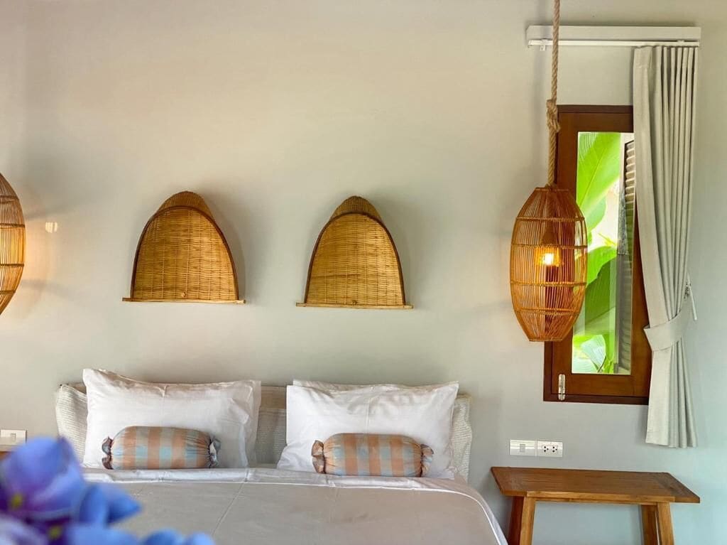 Un dormitorio con cama, dos lámparas de pared, una ventana con cortinas y una mesita de noche de madera.
