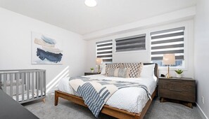 Quarto com cama, mesa de cabeceira e berço.