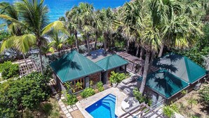 Ein tropisches Resort mit Swimmingpool, Palmen und Blick auf den Ozean.