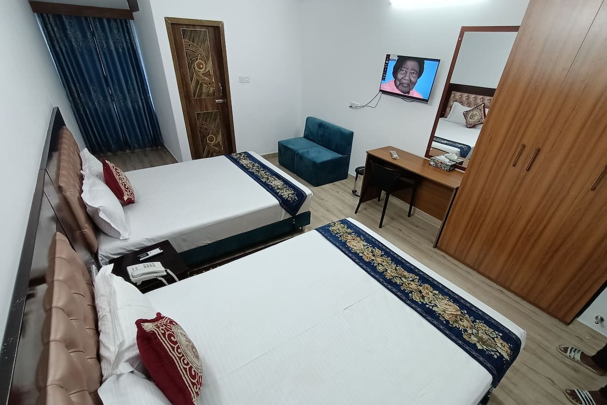 A hotel room with two beds, a desk, a TV, and a wardrobe.