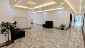 A spacious lobby with a black sofa, potted plants, and a marble floor. - Hotel D-Palace (Dhaka)