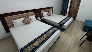 A hotel room with two beds, a desk, a chair, and an air conditioning unit. - Hotel D-Palace (Dhaka)