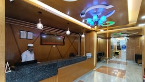 A hotel reception area with a wooden reception desk, a chandelier, and a sign reading "Hotel D-Palace". - Hotel D-Palace (Dhaka)