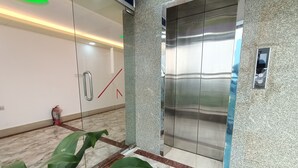 An elevator with a metallic finish, a fire extinguisher, and a green plant in the lobby area. - Hotel D-Palace (Dhaka)