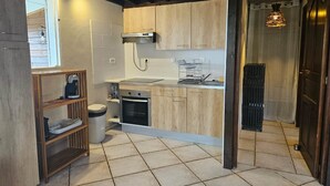 A compact kitchen with wooden cabinets, a built-in oven, and a coffee machine. - Ylang6 Avec vue Panoramique (Saint Leu)
