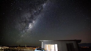 A car parked in front of a building with a large open door, under a starry night sky.