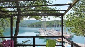 Un espace extérieur abrité, aménagé avec des sièges, et offrant une vue sur un lac et des bateaux.
