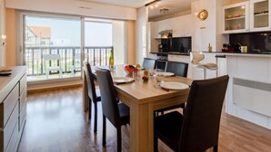 A modern kitchen with white cabinets, a black countertop, and a dining area with a wooden table and black chairs.