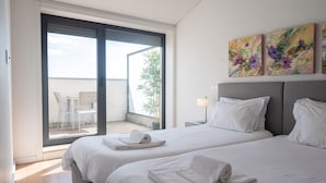 Ett hotellrum med två sängar, en balkong med en stol och en tavla på väggen.