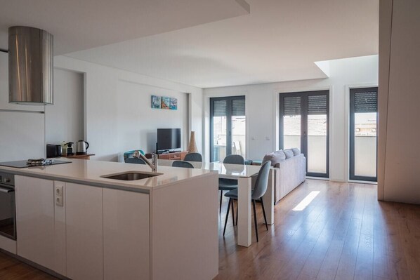 A modern kitchen with a central island, dining area with chairs, and a sofa. - COMFY PORTO - Charming flat with terrace located in Porto centre (Porto)