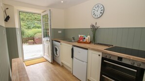 Una cocina compacta con lavadora, un refrigerador pequeño, horno y encimera de madera.