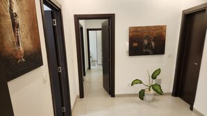 A hallway with a potted plant, a painting, and a door.