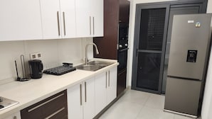 A modern kitchen with white cabinets, stainless steel appliances, and a built-in oven.