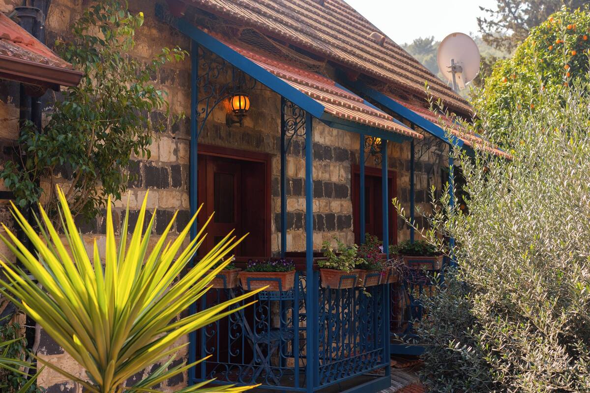 A traditional building with a stone facade, a tiled roof, and a blue balcony railing.