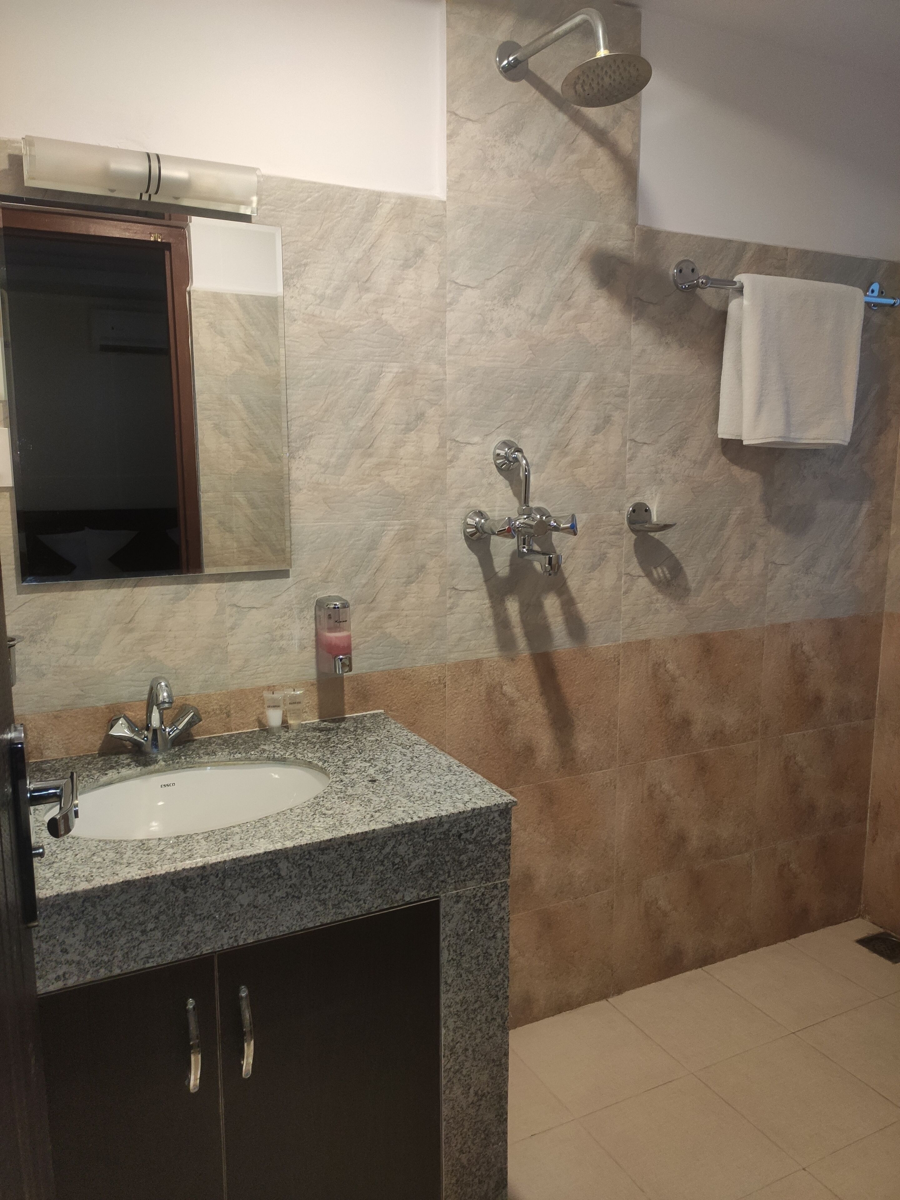 A bathroom with a sink, mirror, shower, and towel rack.
