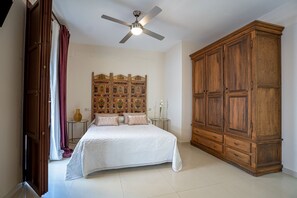 A bedroom with a bed, a wardrobe, a ceiling fan, and a decorative headboard.
