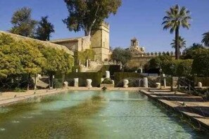 Una piscina con agua cristalina, rodeada de escalones de piedra y estatuas.
