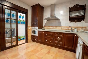 Una cocina con armarios de madera, una campana de acero inoxidable, salpicadero de azulejos y horno empotrado.