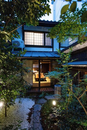 Una casa japonesa tradicional con fachada de madera, un sendero de piedra y un pequeño jardín.