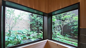 A corner window with a view of a garden with various plants and a wooden fence. - Mitsuda Kamigyo (Kyoto)