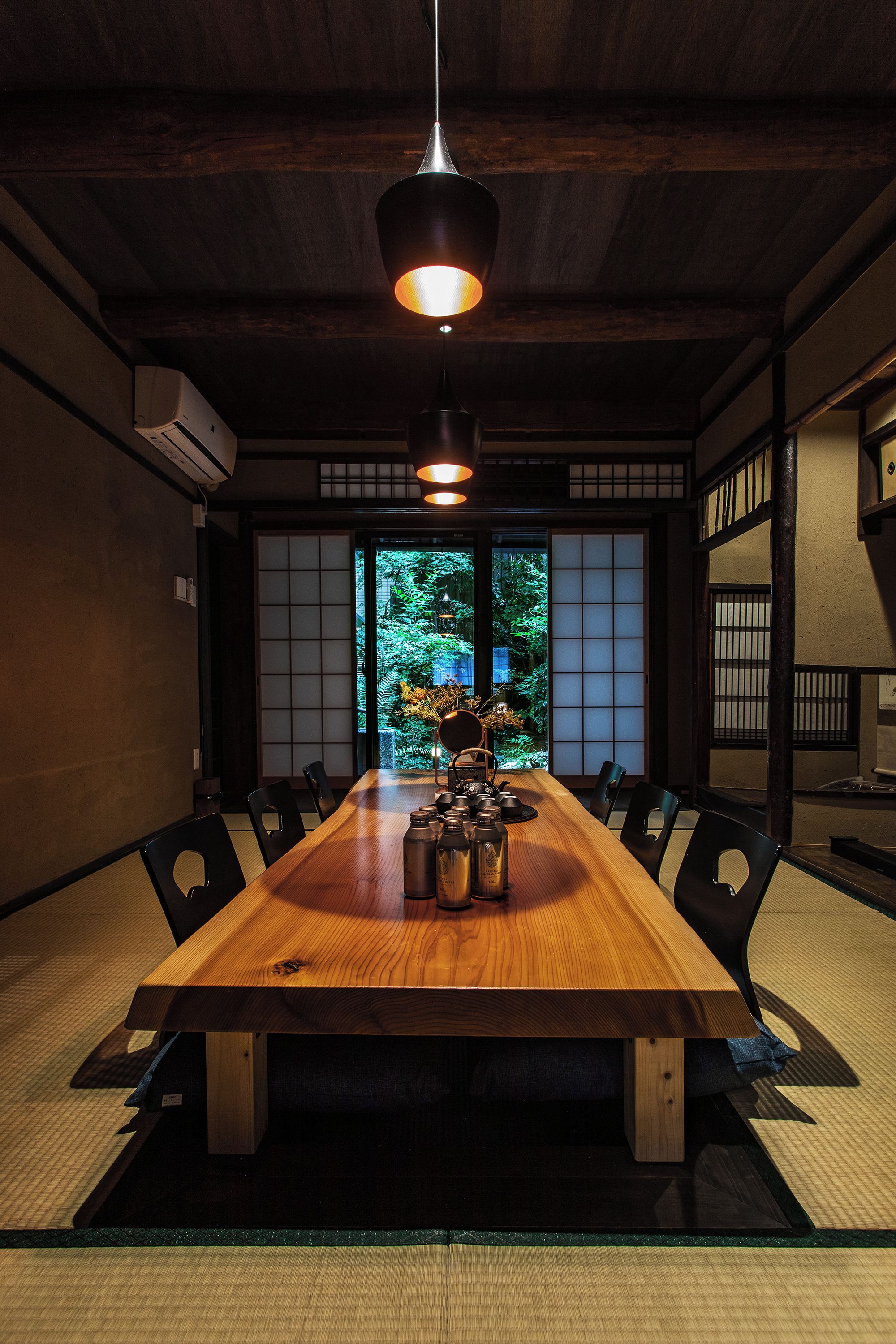 A traditional Japanese-style dining room with a wooden table, tatami mats, and shoji screens.