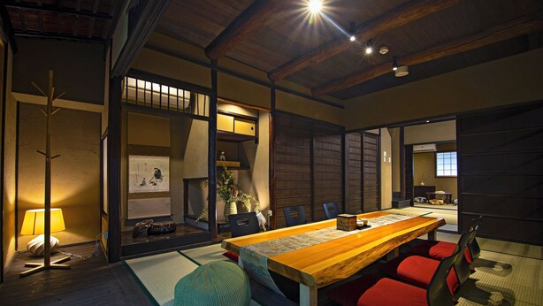 A traditional Japanese room with tatami flooring, a low wooden table, red cushions, and a sliding door. - Mitsuda Kamigyo (Kyoto)