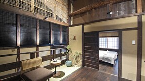 A traditional Japanese room with tatami flooring, a low wooden table, a cushioned bench, and a bed with a futon. - Mitsuda Kamigyo (Kyoto)