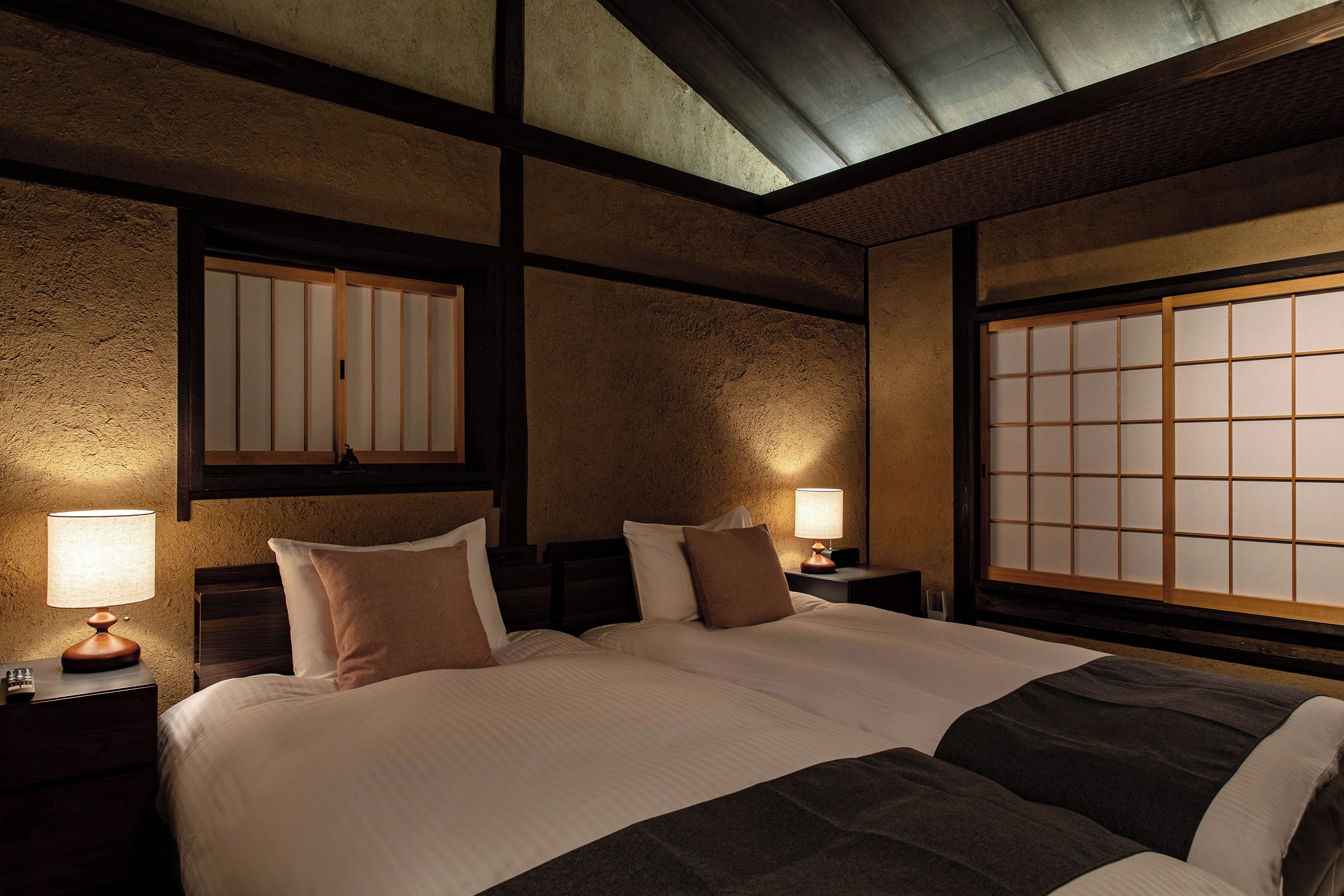 A traditional Japanese-style bedroom with a large bed, wooden headboard, and shoji screens.
