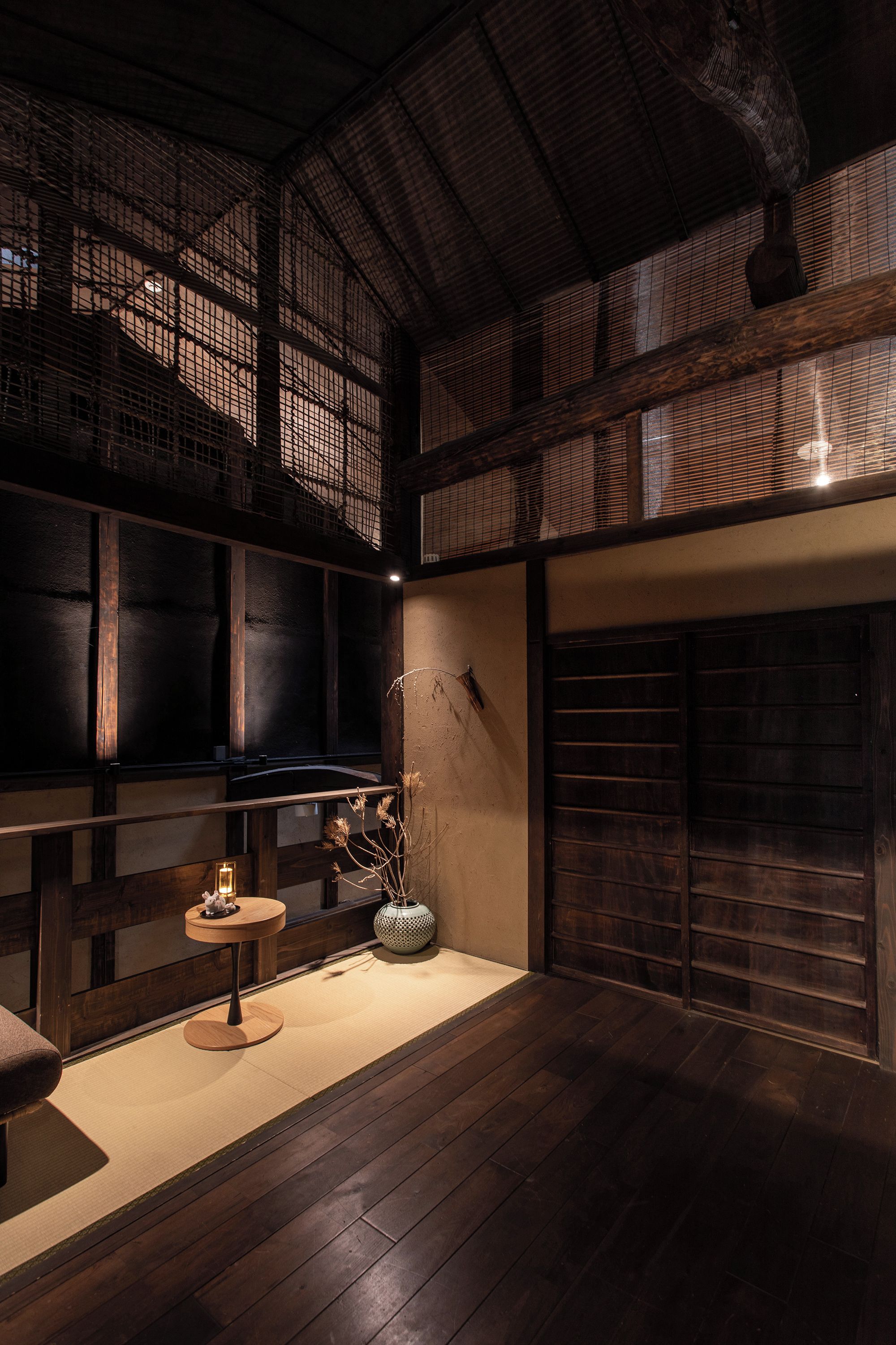A traditional Japanese interior with tatami flooring, a low wooden ceiling, and a sliding door.