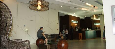 A lobby with a reception desk, seating areas, and a staircase.