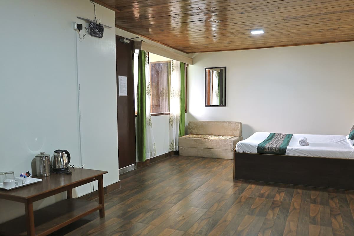 A room with a bed, a small table with a kettle, and a sofa.
