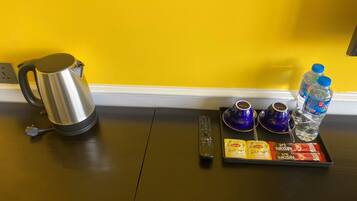 A kitchen area with a kettle, a remote control, and a tray with Lipton tea and water bottles.