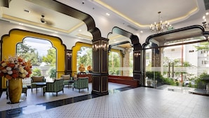 A spacious lobby with a patterned floor, comfortable seating, and large windows offering a view of the outdoors. - Charming Beauty Hotel (Da Nang)
