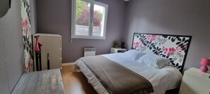 Cozy retreat with a large bed, bedside table, and potted plant.